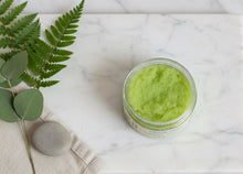 Load image into Gallery viewer, Green jar of Wildflower Soapary Woodland Whisper Exfoliating Sugar Scrub on a textured gray background
