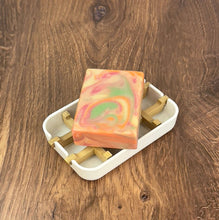Load image into Gallery viewer, Handcrafted Tallow Soap on a white soap dish, showcasing vibrant swirls of orange, green, and pink colors.