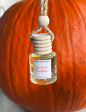 Load image into Gallery viewer, Toasted Pumpkin Hanging Car Diffuser displayed next to a pumpkin, featuring cozy pumpkin spice aromas.