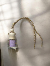 Load image into Gallery viewer, Sandy Beach hanging car diffuser featuring a glass bottle and braided rope for a refreshing car fragrance.