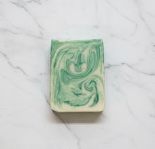 Load image into Gallery viewer, Goat Milk Soap - Eucalyptus bar with green swirls on a marble surface, showcasing its creamy texture and rich lather.