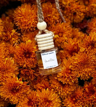 Load image into Gallery viewer, Vanilla Car Diffuser hanging among vibrant orange flowers, adding a fresh scent to any vehicle.