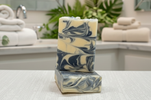 Load image into Gallery viewer, Sandalwood Goat Milk Soap bars with swirls of cream and dark blue on a textured surface, perfect for skin care.