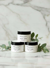 Load image into Gallery viewer, Three jars of Spiced Vanilla body butter surrounded by green leaves on a marble surface.