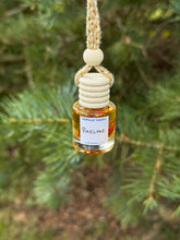 Load image into Gallery viewer, Pinecone Car Diffuser hanging from a tree, releasing fresh pine scent in a natural setting.