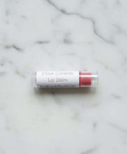 Load image into Gallery viewer, Pina Colada Lip Balm in a tube on a marble surface, perfect for soft and moisturized lips.