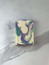 Load image into Gallery viewer, Spa Day Goat Milk Soap with a swirled design of purple and green hues on a marble surface.