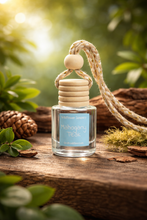 Load image into Gallery viewer, Mahogany Teak Hanging Car Diffuser resting on wood with greenery in the background, offering a warm aroma for your vehicle.