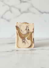 Load image into Gallery viewer, Artisan Woodland Whisper goat milk soap bar with creamy swirls on a marble countertop.