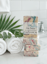 Load image into Gallery viewer, Sea Breeze Tallow Soap bars stacked with tropical leaves, embodying fresh ocean air and creamy buttermilk.

