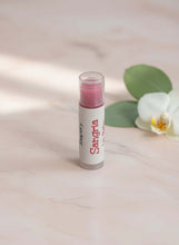 Load image into Gallery viewer, Sangria Beeswax Lip Balm tube packaging on a marble surface with a flower and leaves.

