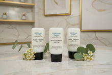 Load image into Gallery viewer, Three bottles of Herbal Indulgence Tallow Lotion on a marble surface with fresh flowers and greenery.
