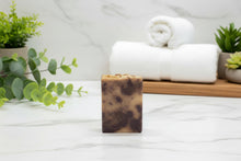 Load image into Gallery viewer, Buttermilk Soap Sandy Beach displayed with fresh greenery and towel for a luxurious skincare experience.
