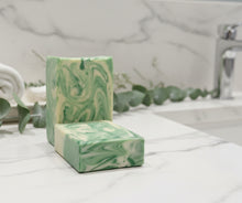 Load image into Gallery viewer, Goat Milk Soap - Eucalyptus bars on a marble countertop with greenery in the background for skincare.
